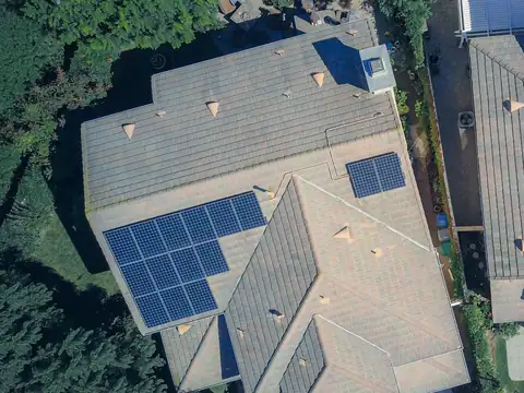 Two arrays of solar panels on the concrete tile roof of a house, seen from directly above